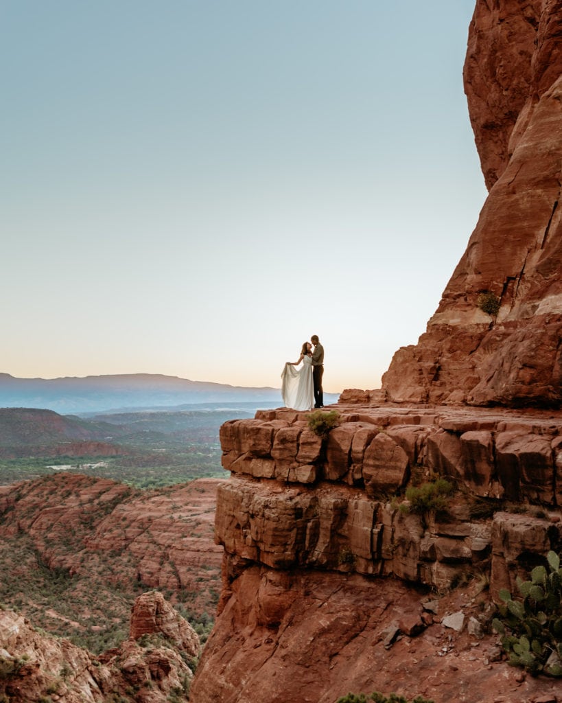 Romantic embrace on the ledge overlooking Sedona at the top of Cathedral Rock
