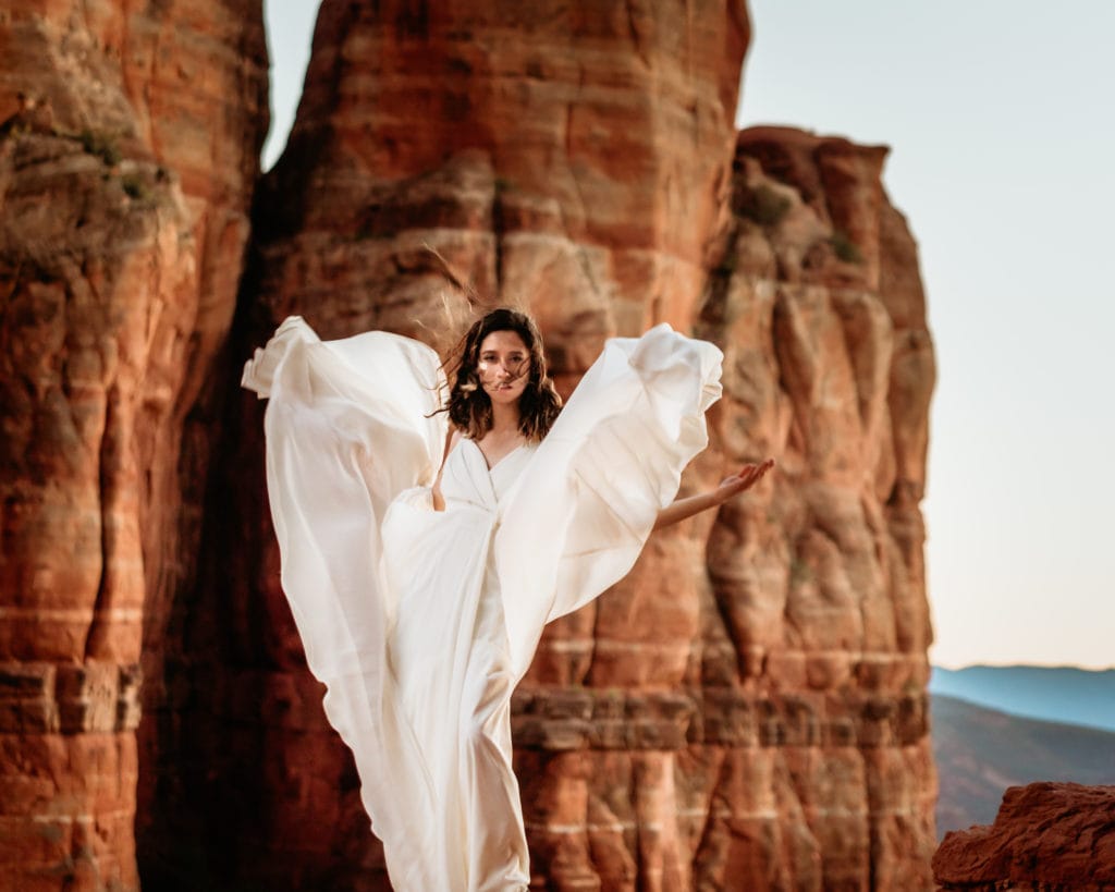 Red rock angel bridals as the wind flies through the flowing dress during sunset in Sedona