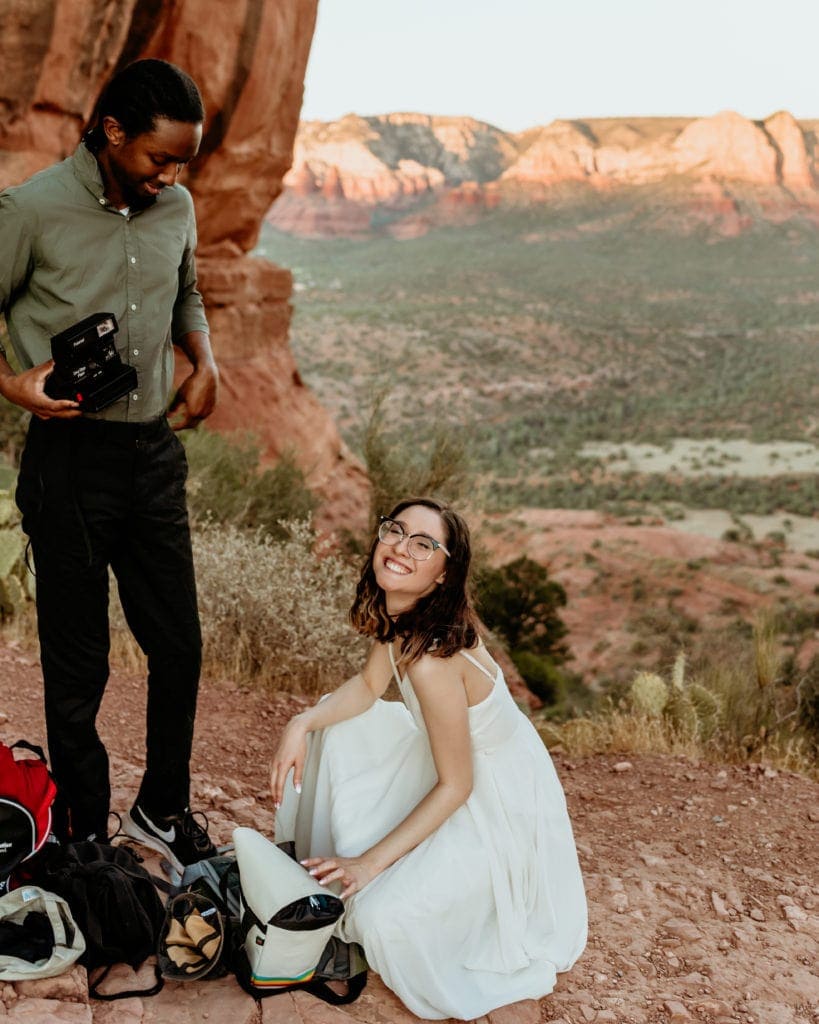 Couple smiling with excitement while getting dressed in their elopement clothing at the top of Cathedral Rock