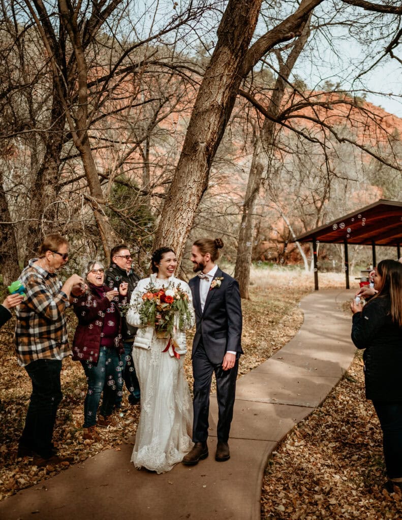 Couple walking through a wall of bubbles during their winter elopement