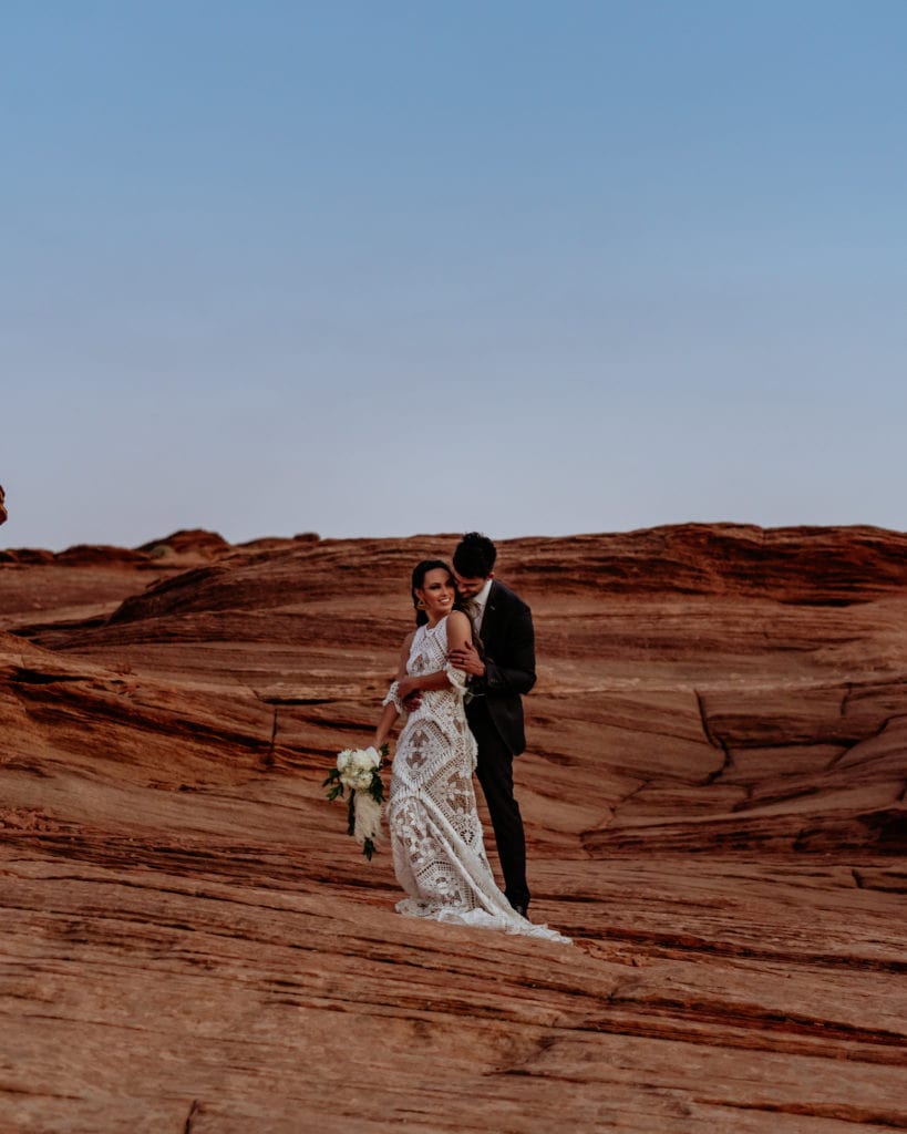 Bride and groom looking off into the sunset from sandstone ledge