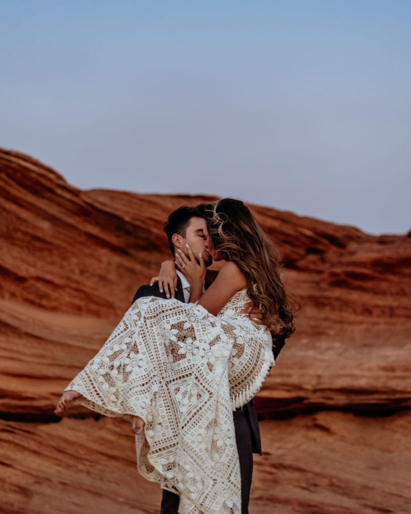 Bride kisses groom as he holds her in his arms