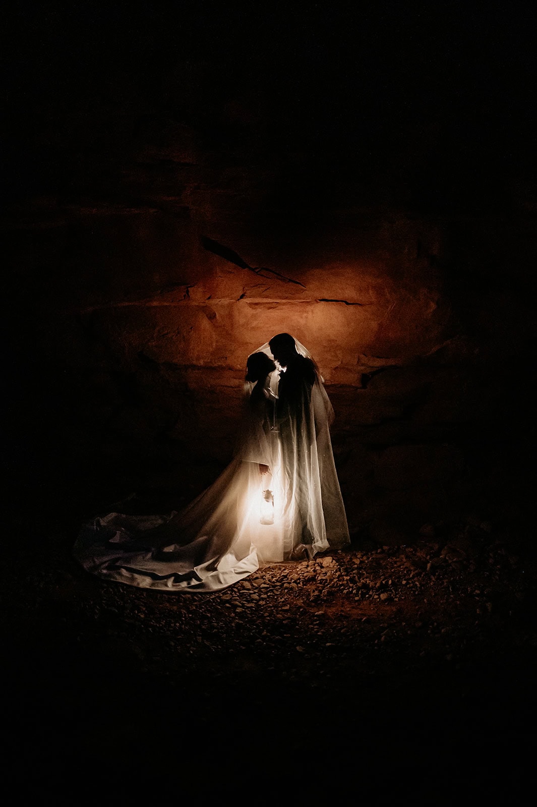 Bride and Groom illuminated by lantern light with a red rock wall behind them by Moab Elopement photographer Stratus Adventure photography