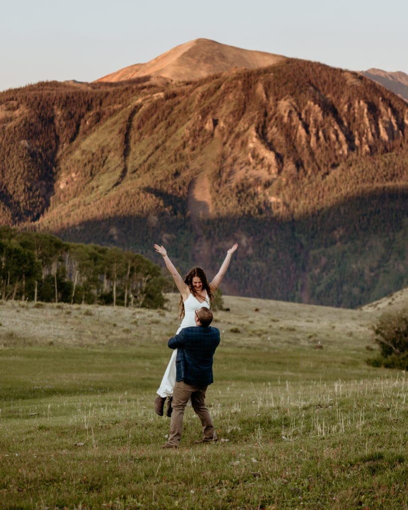 Groom spinning his bride as they run and play during their Colorado elopement