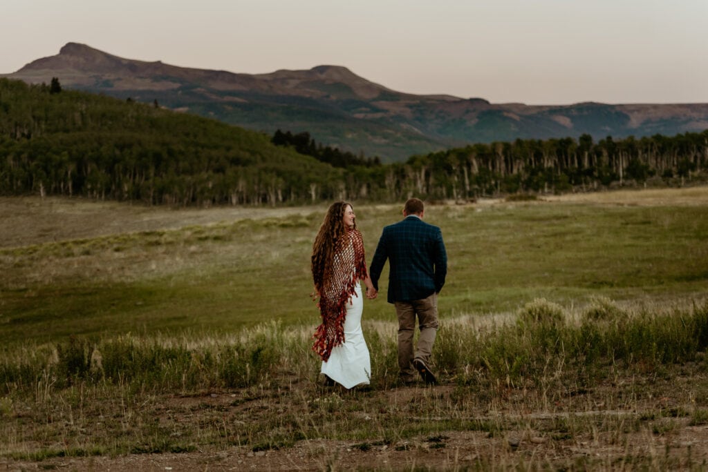 Couple walks hand in hand before the sunrise during their elopement in the San Juan Mountains, photographed by San Juan Mountains Elopement Photographer Shannon Durazo