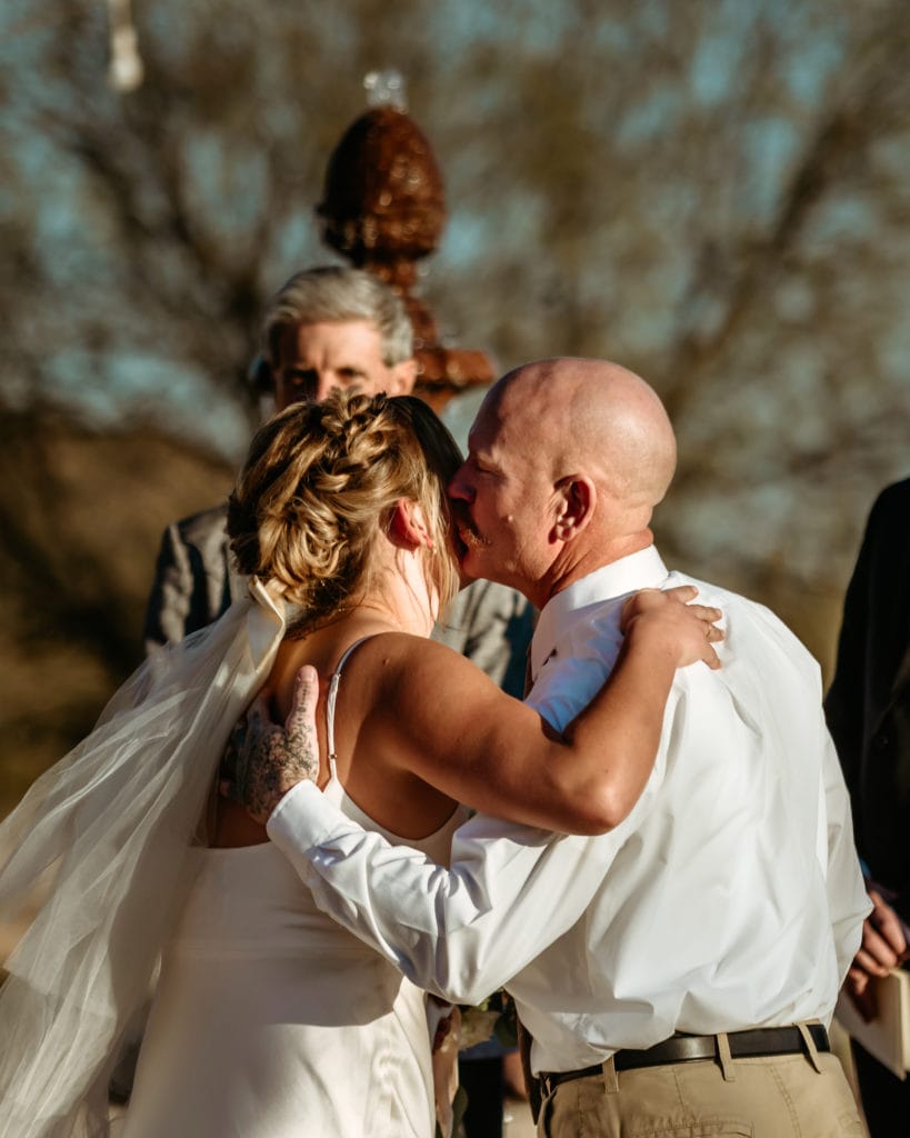 Father kissing bride before intimate wedding ceremony