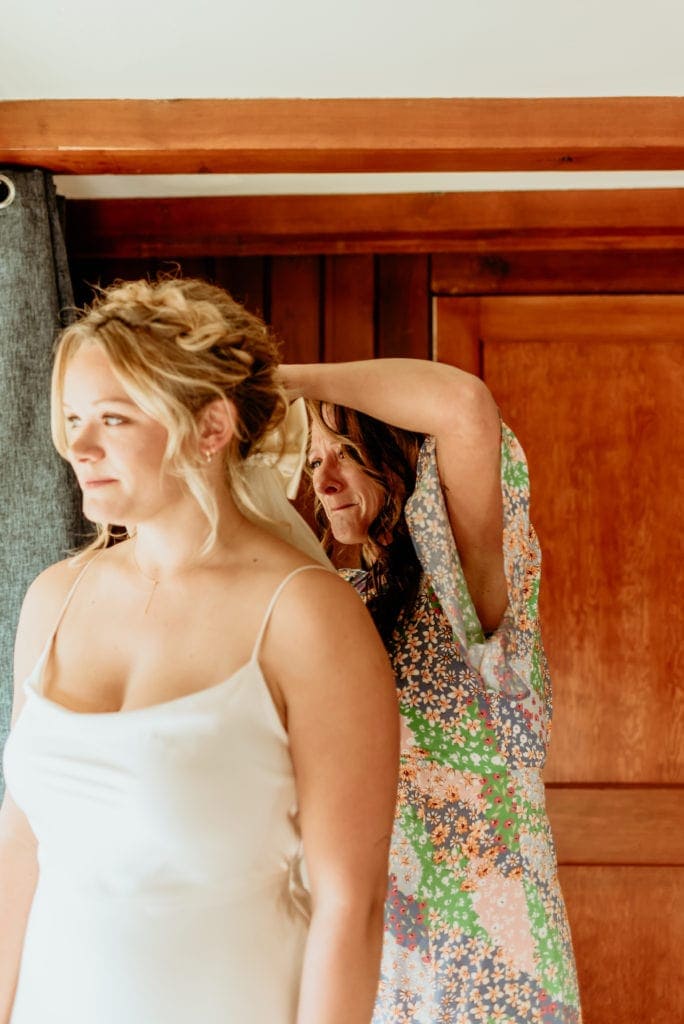 Mom pinning grandmother's vintage veil on bride for wedding day