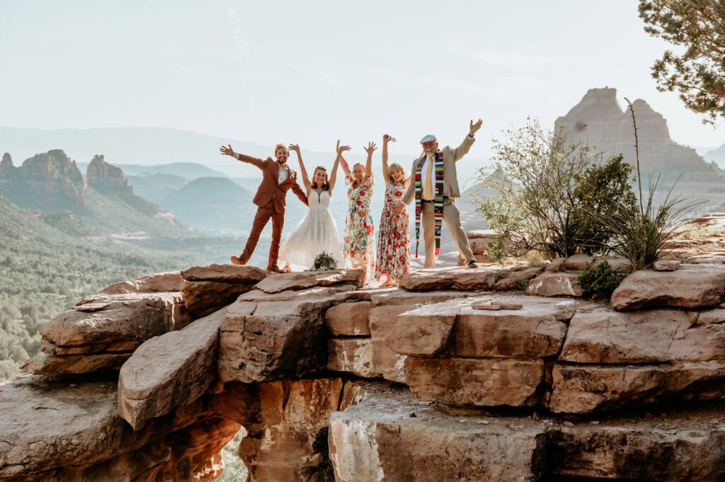 Elopement couple and their parents celebrating with hands up cheering and having a great time