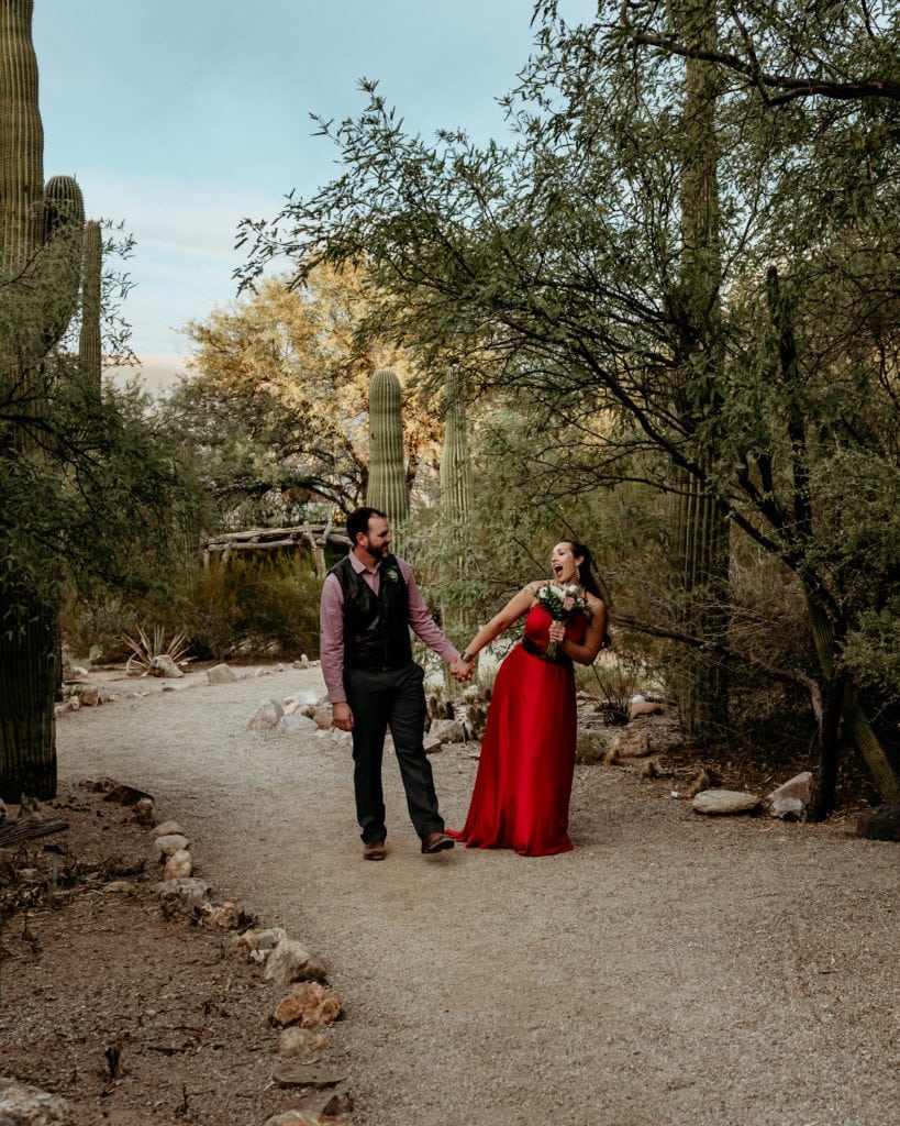 Bride and groom walk hand in hand through the desert landscape at the Tucson Botanical Garden