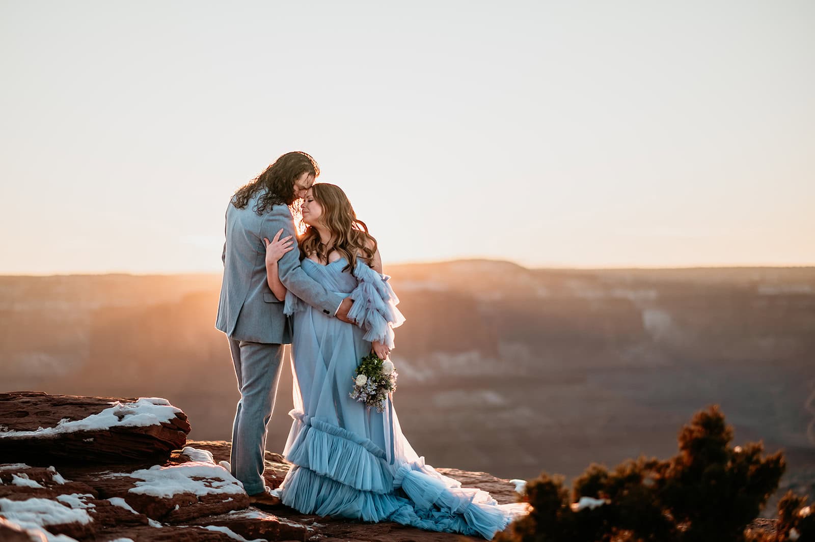 couple embrace during golden sunset light overlooking the canyons by Moab Elopement photographer Stratus Adventure photography