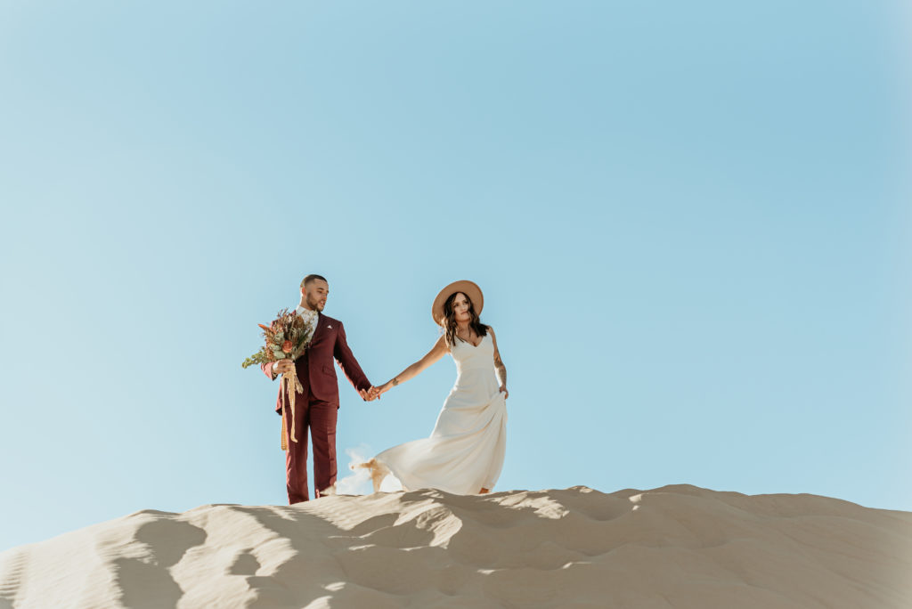 Couple wandering across the desert landscape at their sand dune elopement