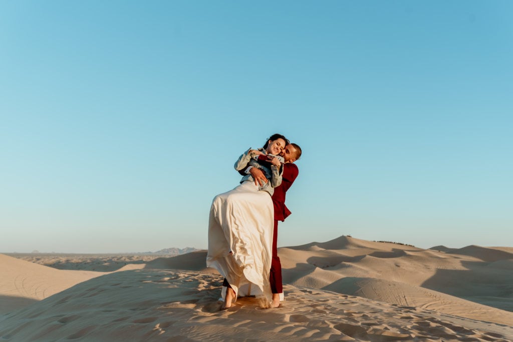 Groom swinging and spinning his wife on top of sand peaks at Glamis Sand Dunes