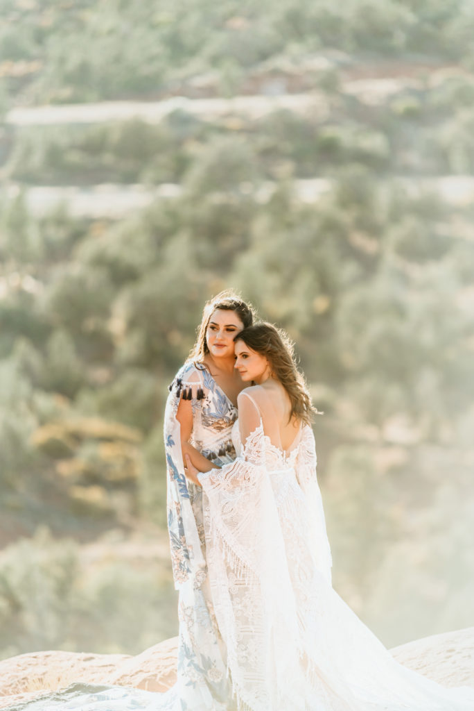 Warm light surrounds brides in romantic embrace