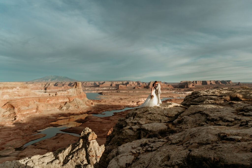Couple embracing on a cliff overlooking Lake Powell by Arizona elopement by Stratus Photography