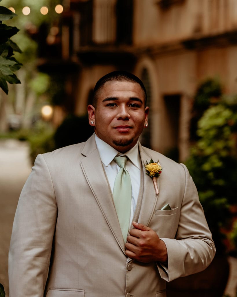 Groom in tan suit, mint tie, and yellow boutonniere