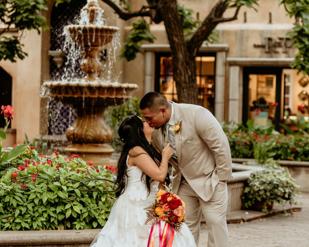 Bride pulling her groom down for a kiss in the Tlaquepaque courtyard in front of the fountain