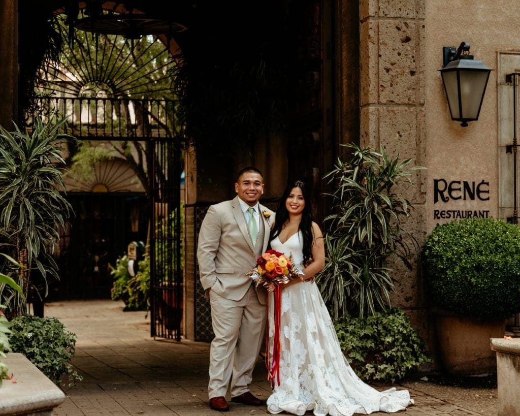 Old world stone walls and lush greenery surround bride and groom at Tlaquepaque