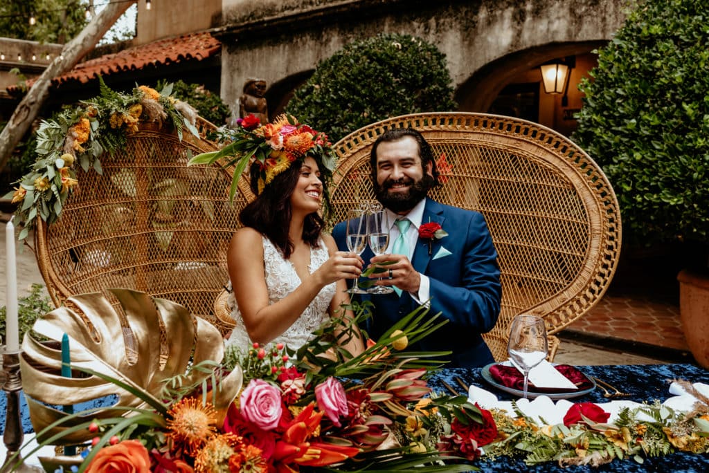 Wedding couple laughing at their tropical flower covered sweetheart table in Sedona, Arizona