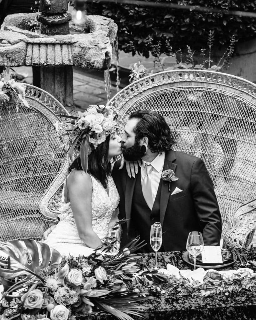Bride and groom kiss with Tlaquepaque courtyard fountain seen behind their sweetheart table