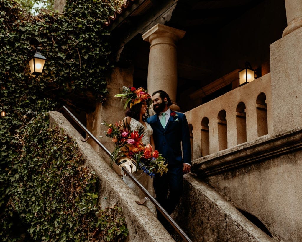 Deep green vines on the walls around bride and groom as they descend the stairs