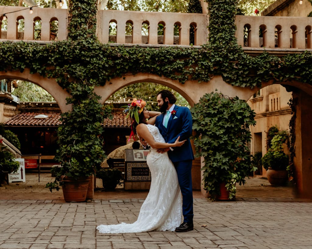 Groom dipping bride in ivy lined courtyard at Tlaquepaque in Sedona
