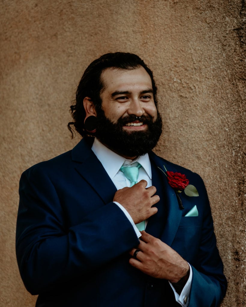 Groom smiling as he adjusts his tie
