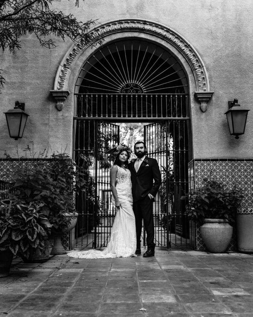 Black and white of bride and groom in front of gate at Tlaquepaque arts and crafts village
