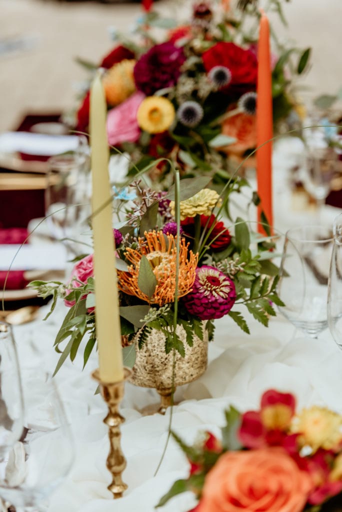 Floral center pieces flanked by colorful candles during a Tlaquepaque wedding reception