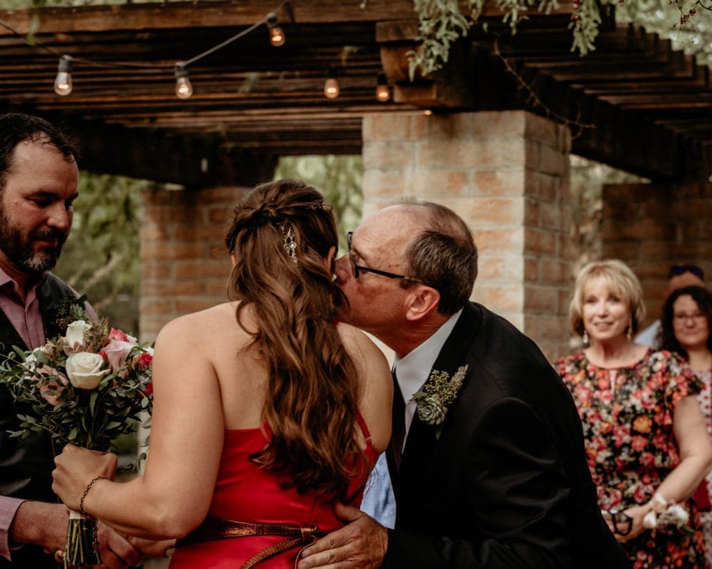 Father kissing bride after waking her down the isle
