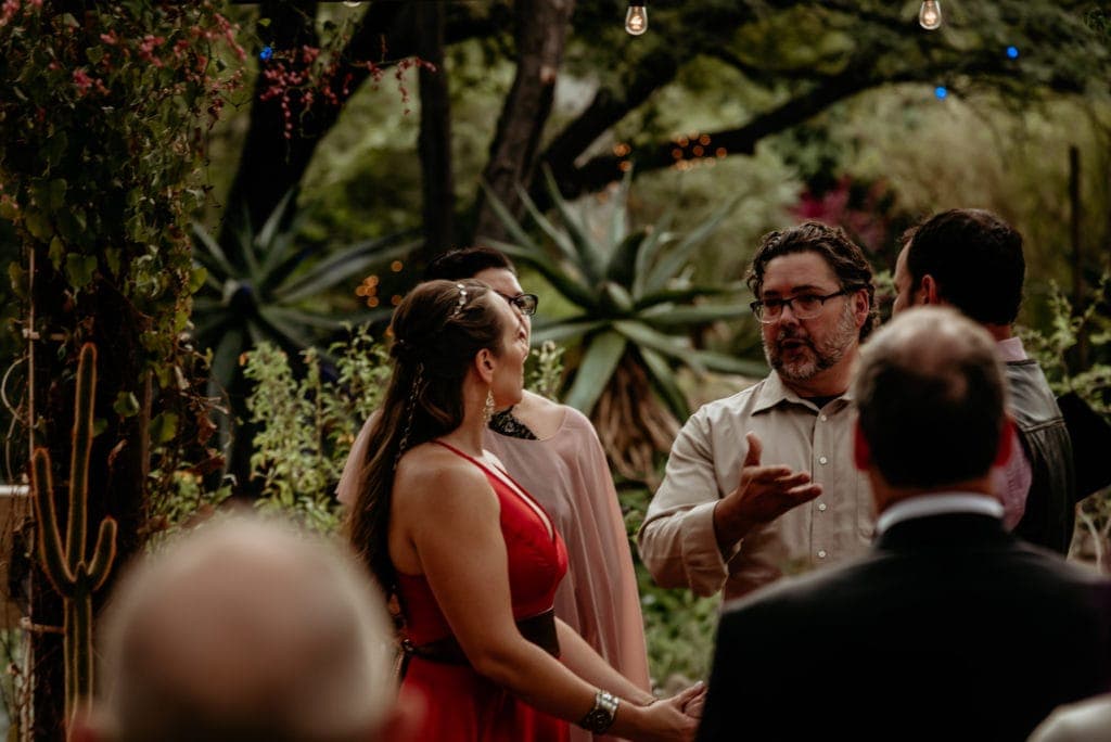 Bride listening to officiant with the lush desert greenery behind them