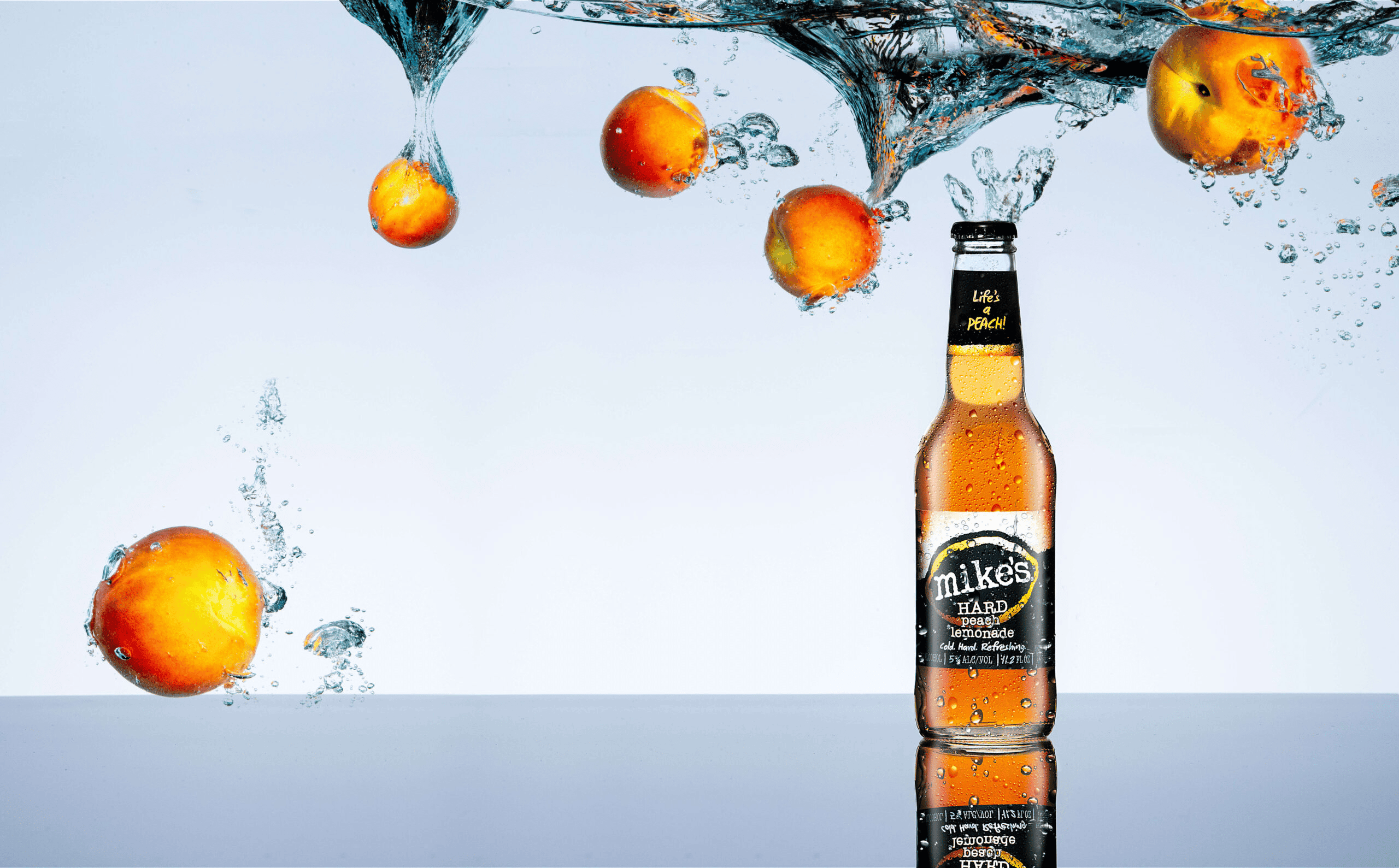 Mike's Hard Peach beer with splashing peaches, illustrating video production and brand photography services.