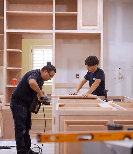 Carpentry workers building wooden cabinets in a workshop.