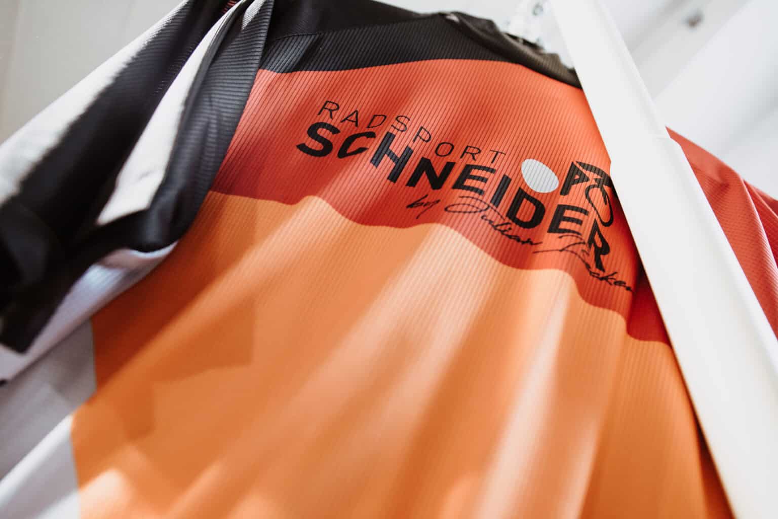 Radsport- und Mountainbike-Jacke mit TeamRS-Logo in Orange und Schwarz.