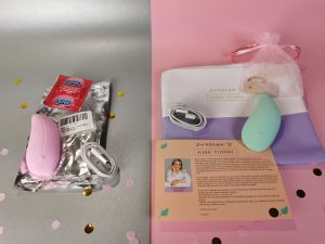 Links ligt de ali toy, in een plastic zakje, met condoom met chinese tekst en de oplader. Rechts ligt de l'eve met zijn verpakking, flyer en oplaadkabeltje.