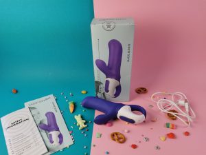 De magic bunny ligt voor de verpakking, waar je de achterkant van ziet. Daar naast ligt een gebruiksaanwijzing en een boekje met safety instructies. Er ligt ook een usb-oplaadkabeltje.