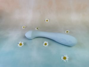 De dame arc ligt op een blauw met roze ondergrondje, met wat witte bloemetjes er omheen. De dame arc is heel lichtblauw en is gebogen, een beetje zoals de hoofdletter j.