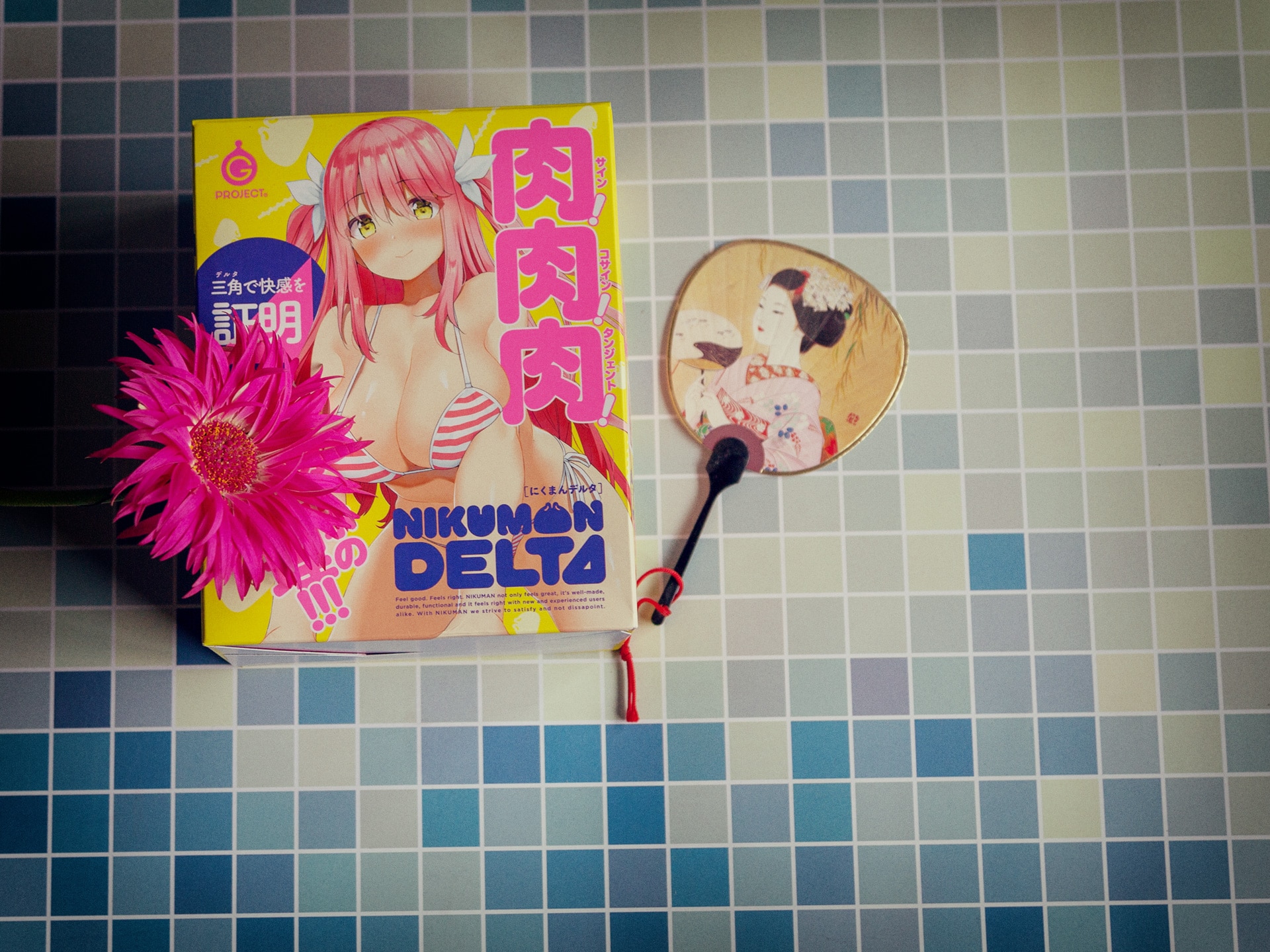 De doos van de niku-man delta met daarbij een bloem en een japanse waaier