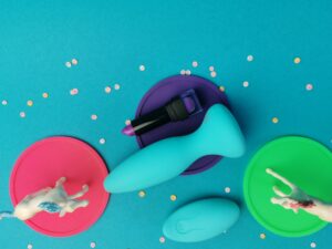 De doc johnson a play thrust adventurous stotende buttplug van boven gezien, met daarnaast een lipstick en de afstandsbediening.
