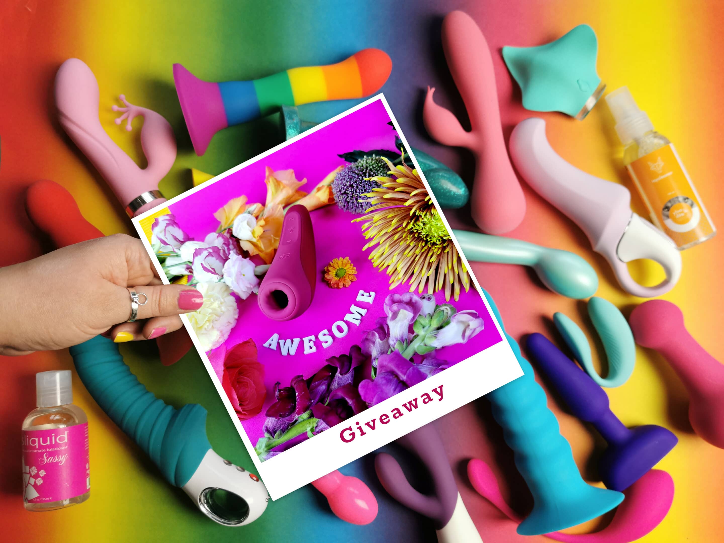 Je ziet een (te grote) polaroid foto met daarop de Satisfyer Curvy 1+ boven een ondergrondje vol met allerlei gekleurde sextoys.