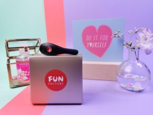 De fun factory be one ligt op het doosje. Het doosje is een beetje goudkleurig met daarop het ronde, rode fun factory logo.