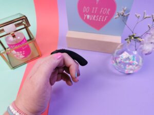 De fun factory be one tussen mijn vingers, van de zijkant gezien. Je ziet dat het er een beetje uitziet als een extra vingertje.