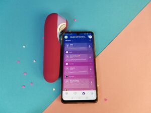 De satisfyer dual love naast een telefoon waarop de app aanstaat