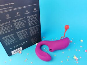 De lelo enigma  ligt voor de verpakking, waar je de achterkant van ziet. De doos is zwart met gouden letters.