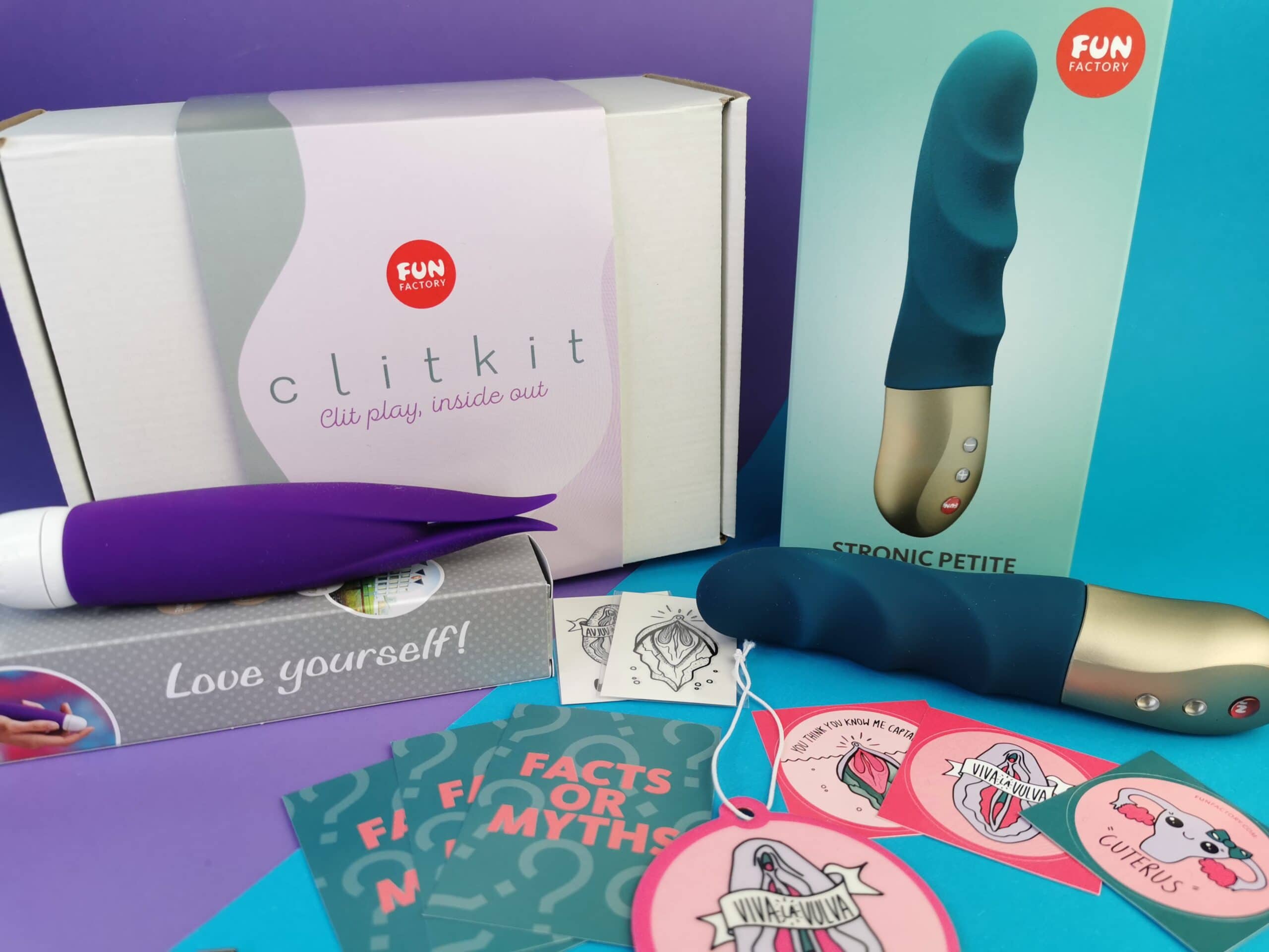 Je ziet de verpakking van de Fun Factory Clit Kit, de verpakkingen van de toys, de toys zelf en de stickers en andere goodies die in de doos zitten.