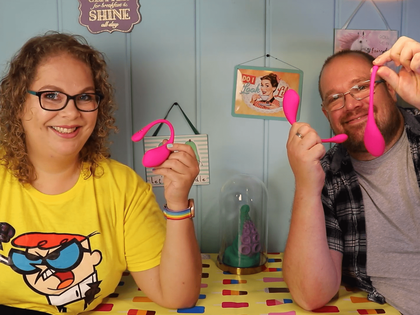 Tess en Jay zitten aan de keukentafel. Ze houden de Lovense Lush 1, 2 en 3 vast.