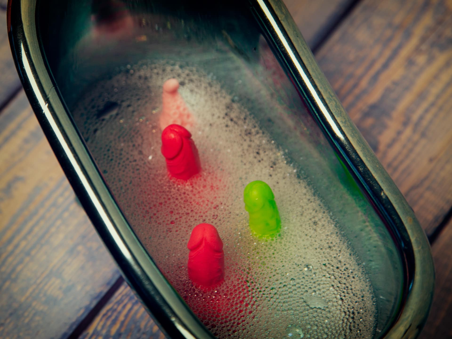 Hoe verzorg je de penis? Een foto van een aantal mini dildo's in een miniatuurbad met een sopje