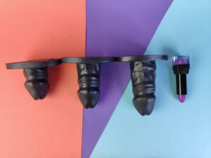 De dildo's van de  mister b deepthroat trainer gag  op een rij, met een lipstick er naast.