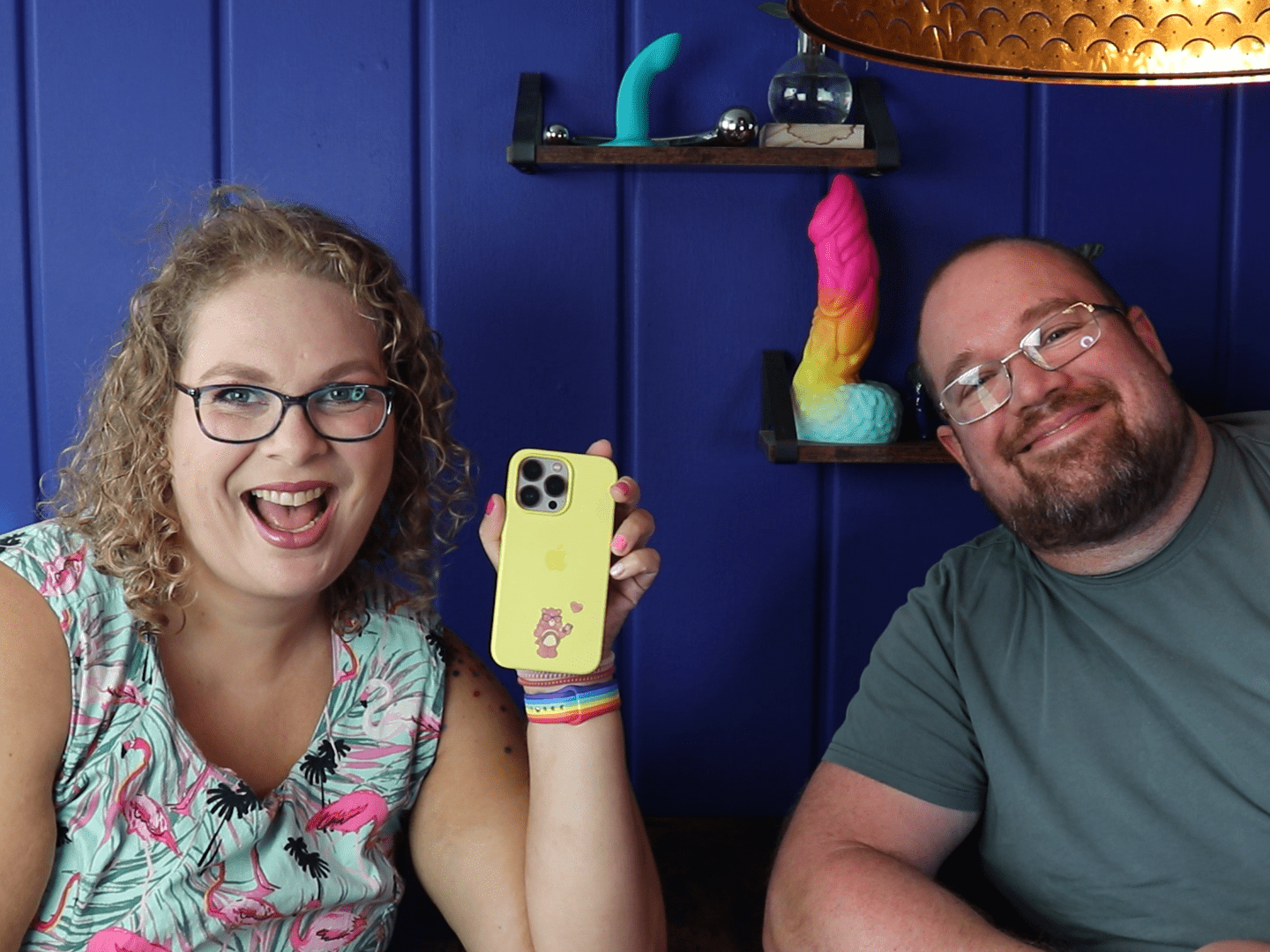 Tess en Jay zitten aan de keukentafel en Tess houdt haar telefoon vast.