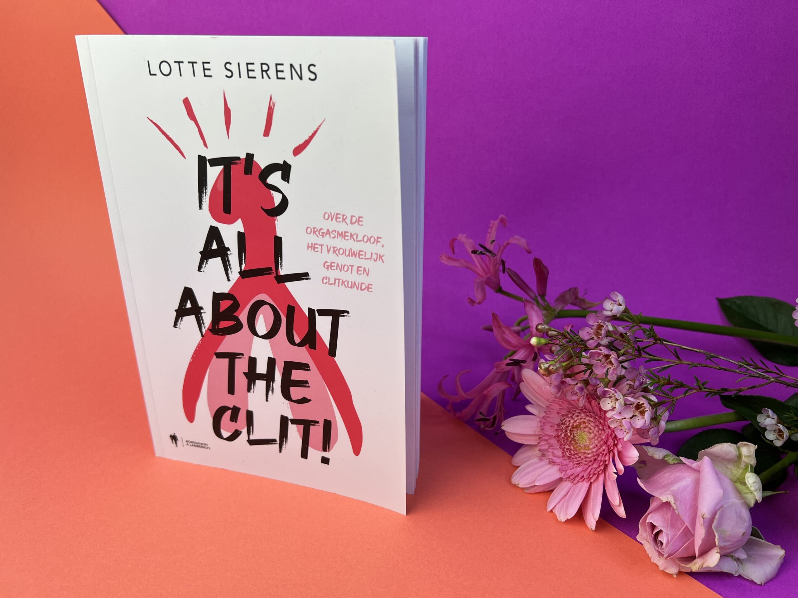 Het boek It's all about the clit door Lotte Sierens op een gekleurd ondergrondje, met bloemen.