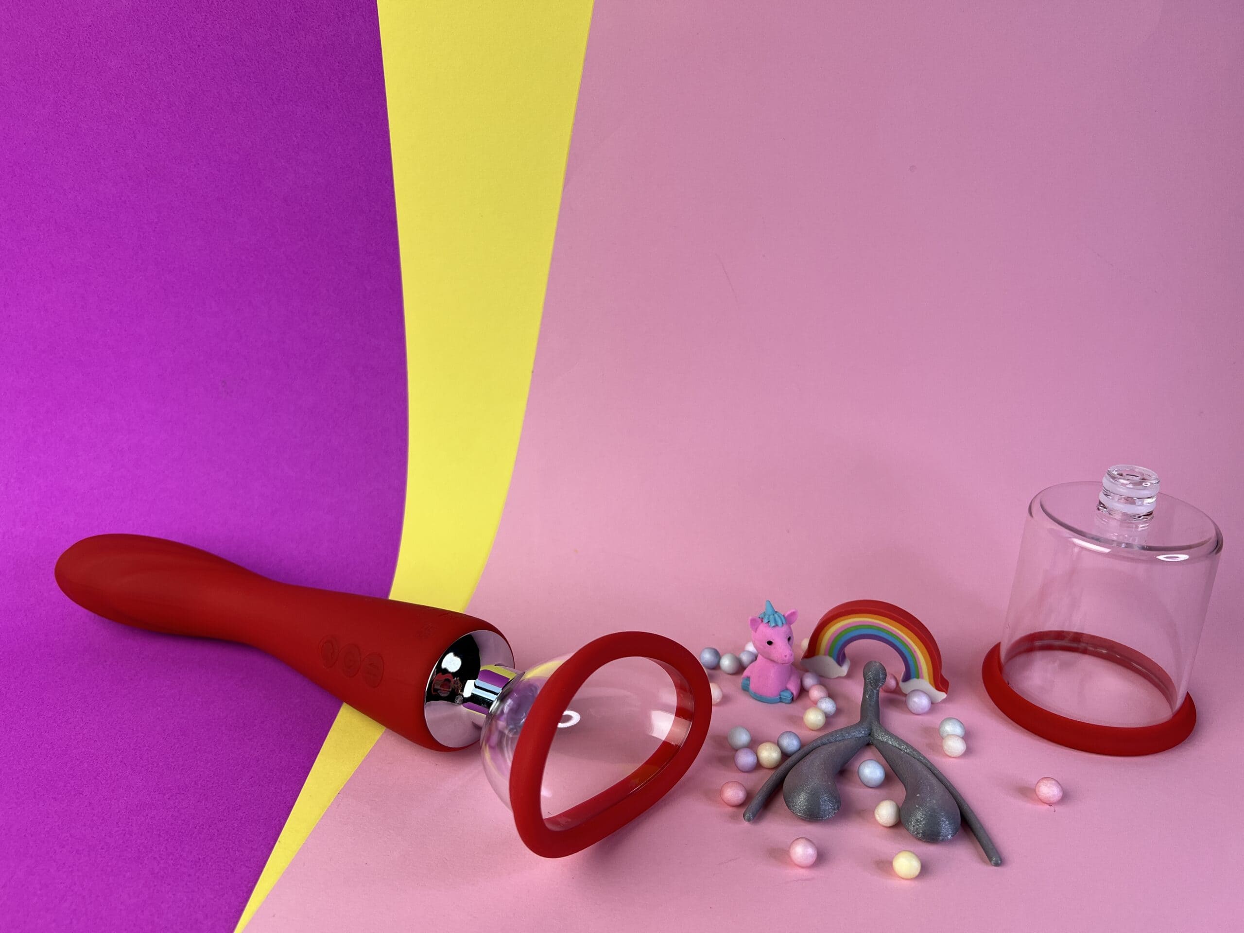 De Dream Toys Georgia ligt op een gekleurd ondergrondje. Er naast ligt een 3D clitoris en daar naast het andere vacuüm cupje.